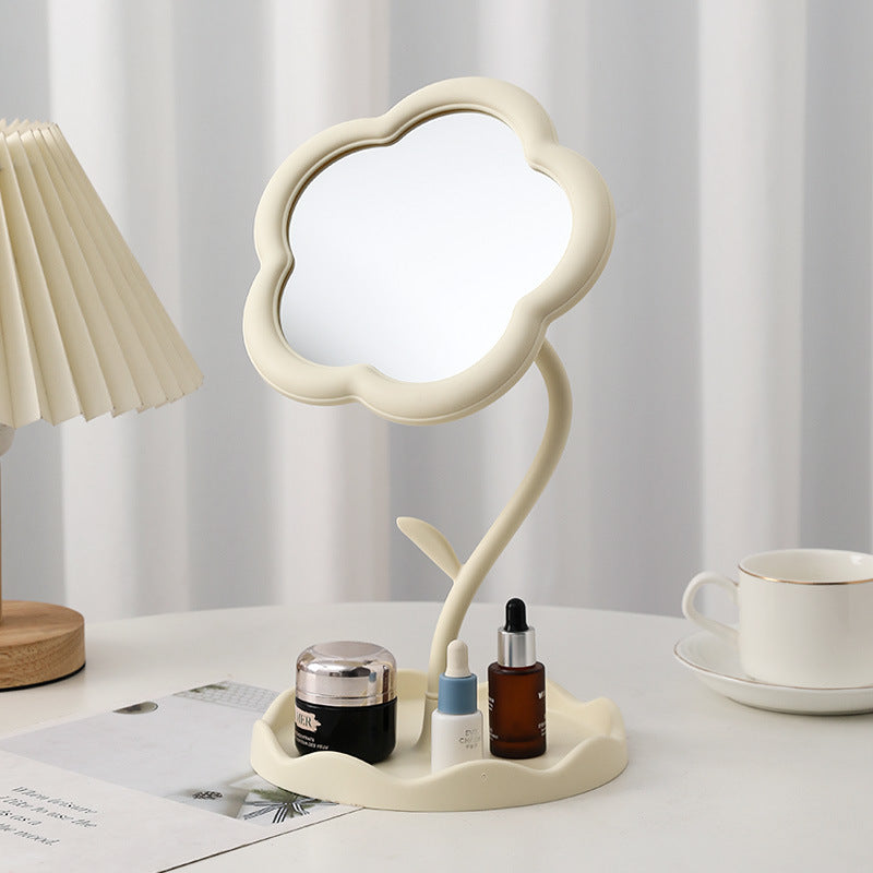 White flower-shaped tabletop mirror on a vanity with skincare bottles