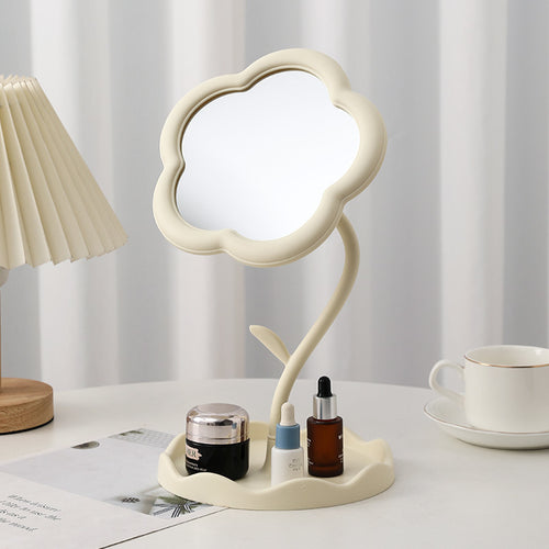 White flower-shaped tabletop mirror on a vanity with skincare bottles